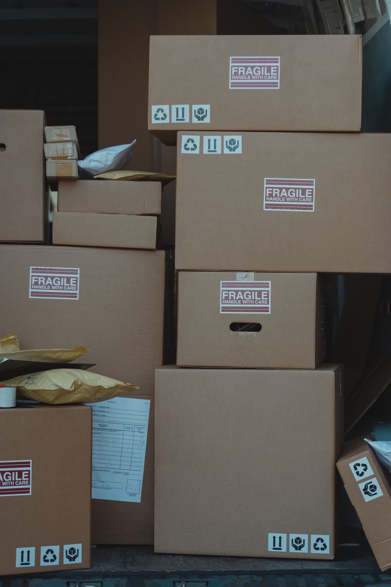 Gestapelde verzenddozen met breekbaar-stickers en pakketten