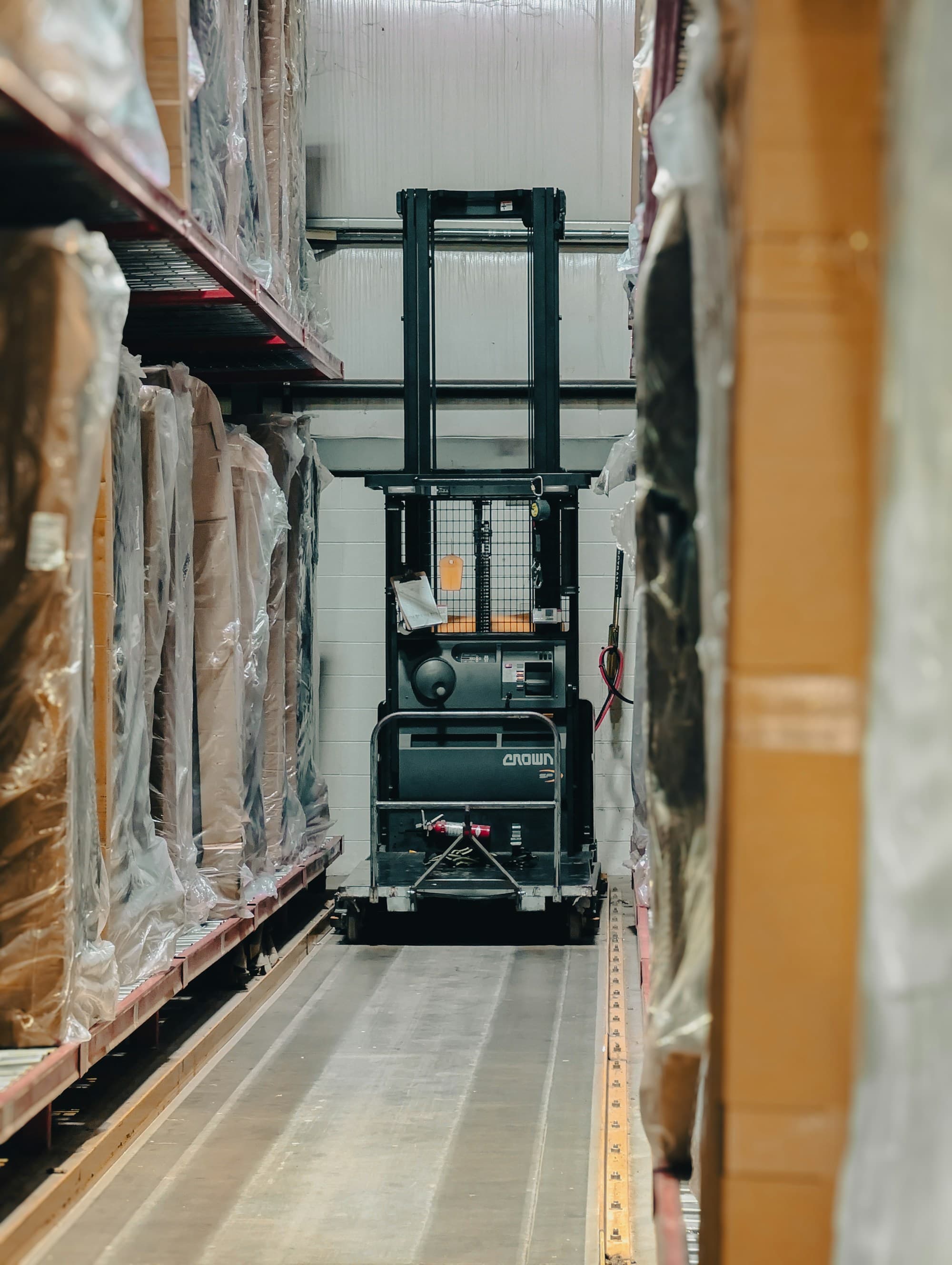Gang in een magazijn met hoge rekken vol dozen en pallets