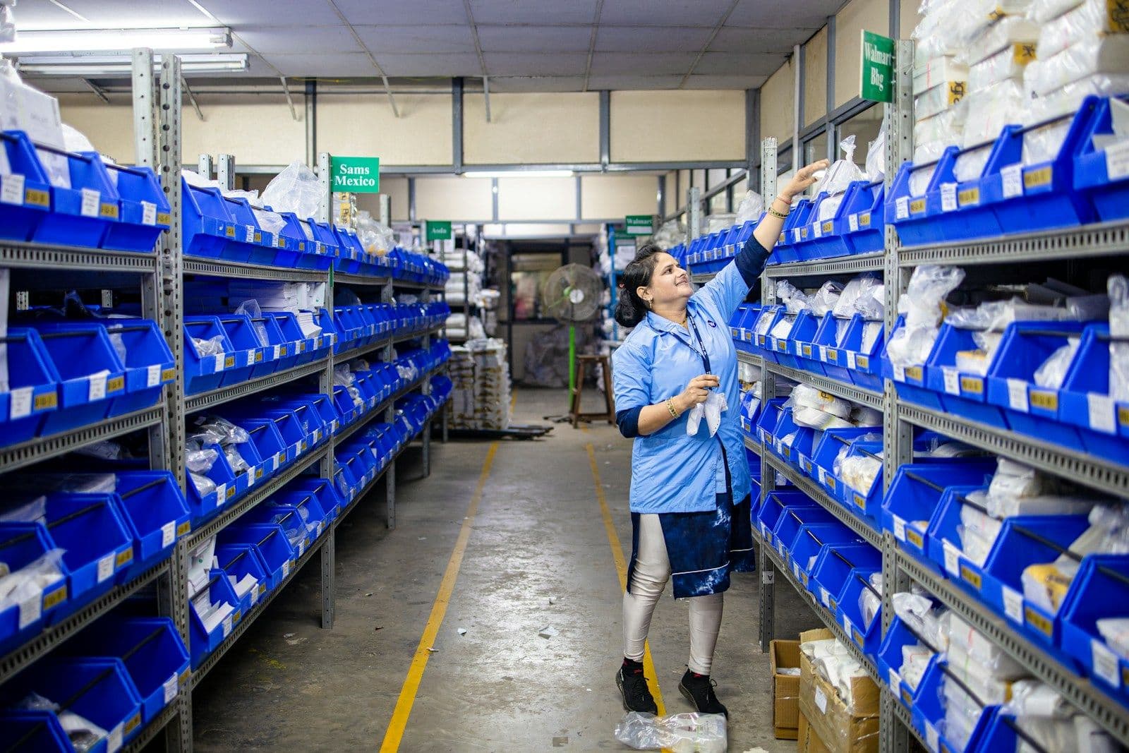 Magazijnmedewerker neemt een artikel uit een rek met blauwe bakken